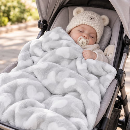 ébé dort dans une poussette avec une couverture bébé grise à motifs cœurs