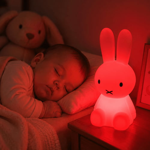 Bébé dort paisiblement à côté d'une veilleuse lapin rouge diffusant une lumière tamisée