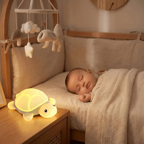 Bébé dort paisiblement dans sa chambre éclairé par la douce lueur d'une veilleuse tortue à la lumière chaude et tamisée