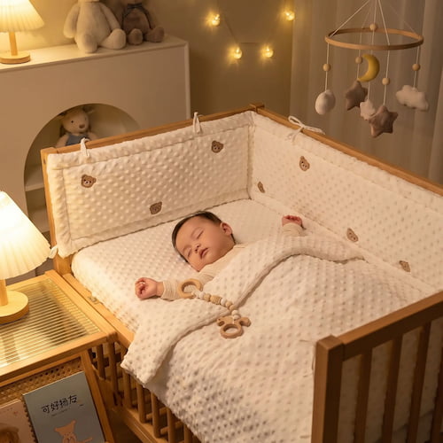 Bébé dort paisiblement dans son lit avec un tour de lit respirant motif ours