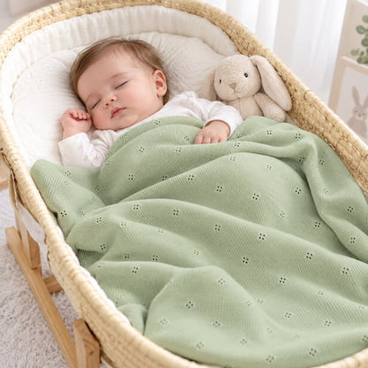 bebe dort paisiblement dans un couffin en osier sous une couverture bebe tricot verte