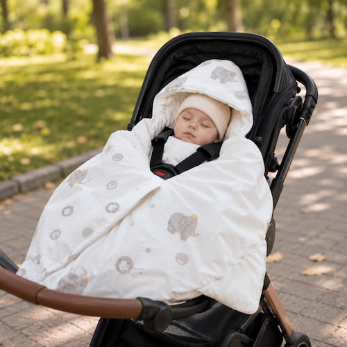 Bébé dort paisiblement dans une poussette protégé par un nid d ange siege auto au motif éléphant gris