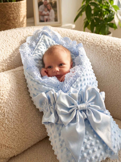 bebe emmaillote dans un nid pour bebe bleu a pois avec dentelle et grand papillon 