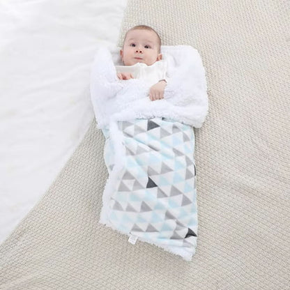 Bébé enveloppé dans une couverture bébé bleue à motifs géométriques.