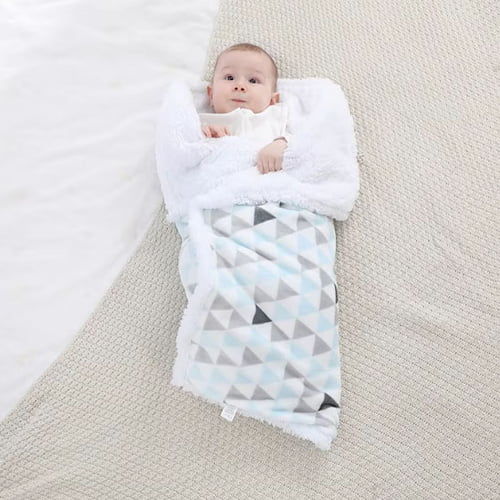 Bébé enveloppé dans une couverture bébé bleue à motifs géométriques.