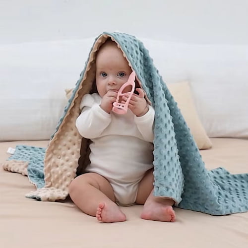 Bébé est enveloppé dans une couverture bébé vert et beige douce adaptée aux moments de détente