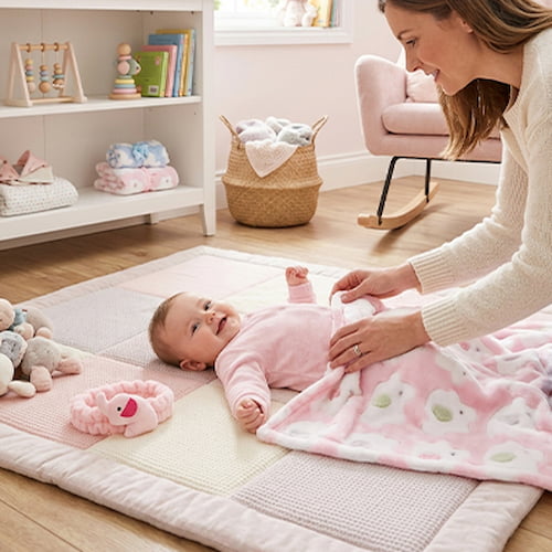 Bébé joue sur son tapis avec une couverture bébé polaire rose douce à motifs d’éléphants