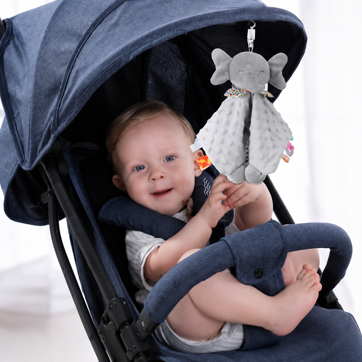 bebe souriant dans poussette jouant avec doudou elephant gris tout doux
