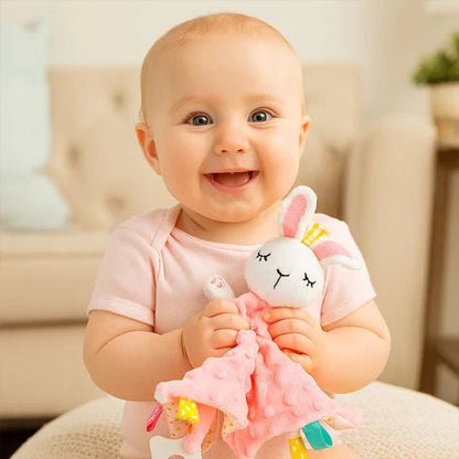 bebe souriant tenant un doudou lapin rose avec un corps de couverture rose pointille