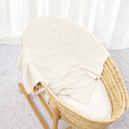 couverture bebe tricot blanche douce et ajouree presentee dans un couffin en osier
