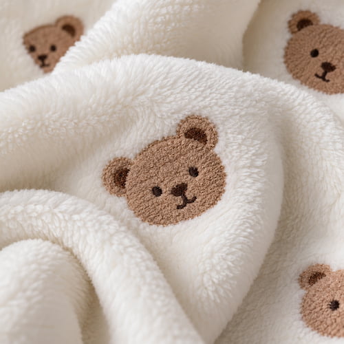 Gros plan sur le motif ours de la couverture bébé blanche douce et moelleuse