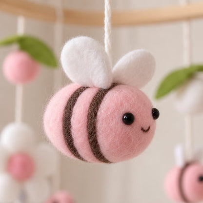 Gros plan sur une abeille rose en feutrine du mobile bebe avec détails doux et finition soignée