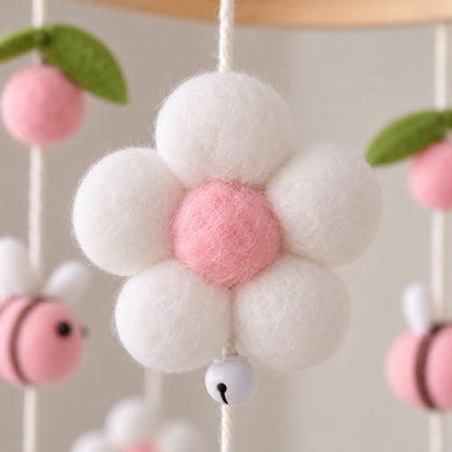 Gros plan sur une fleur rose en feutrine du mobile bebe avec abeilles roses