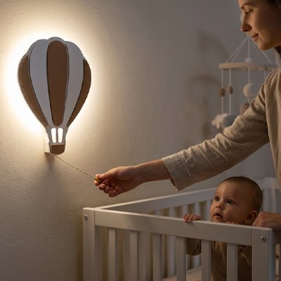 Maman allume une veilleuse murale bebe montgolfière dans la chambre de son enfant