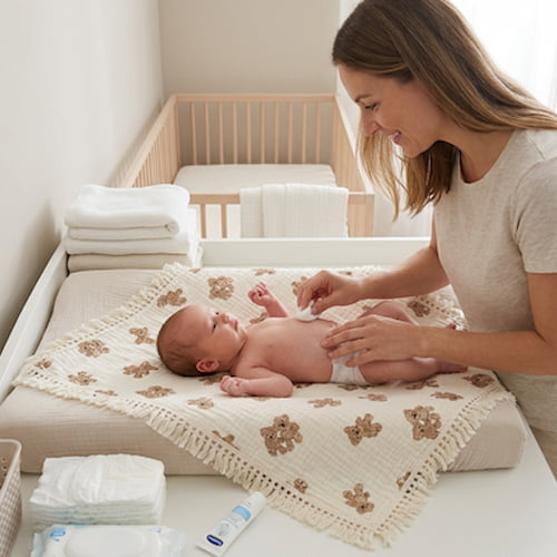 Maman change bébé sur une couverture bébé à motifs ours douce et décorative
