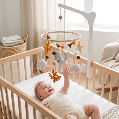 Mobile bebe coloré avec baleine  blanche, étoiles et fleurs suspendus au-dessus du lit