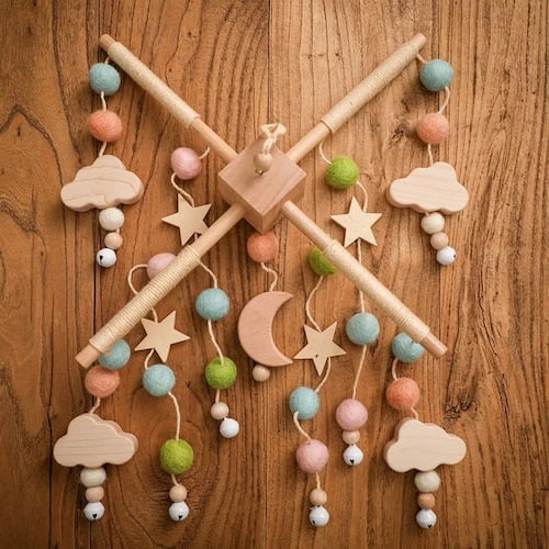 Mobile bebe en bois avec etoiles lunes et nuages aux couleurs vert rose presente a plat