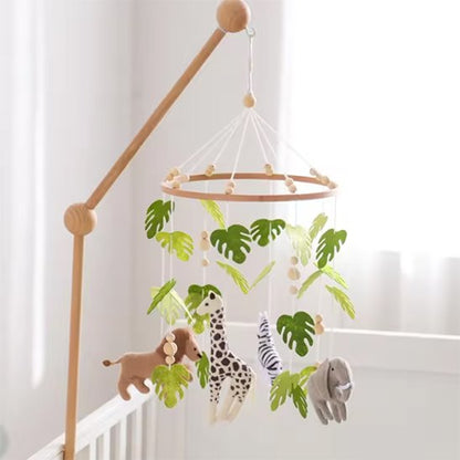 Mobile bébé motif safari installé au-dessus du berceau avec des animaux et des feuilles tropicales