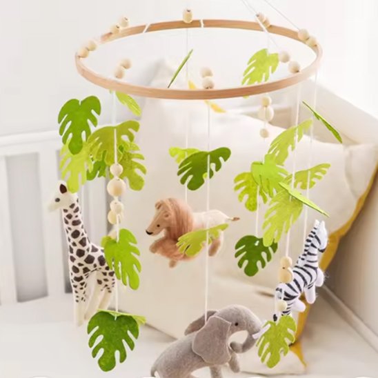 Mobile bébé safari en bois avec girafe, éléphant, zèbre et lion suspendus parmi des feuilles vertes.