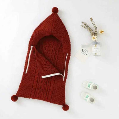 nid d ange cosy en maille tricotee rouge avec capuche a pompon et motif torsade
