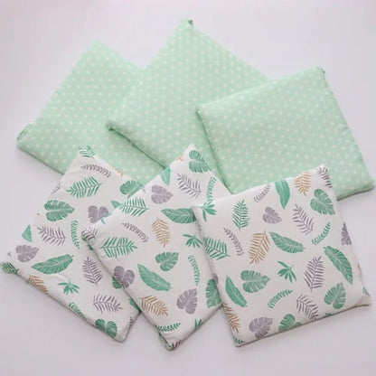 Tour de lit bebe vert à motifs feuilles présenté en plusieurs pièces
