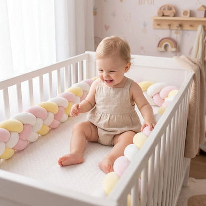 Tresse de lit bebe rose jaune et blanc autour du lit avec bébé assis qui sourit et joue dans son lit