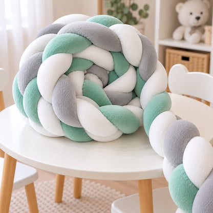 Tresse de lit bebe vert gris et blanc roulée sur une table pour montrer sa texture douce et son tressage épais