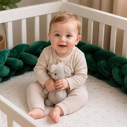 Tresse de lit vert foncé installée autour du lit de bébé