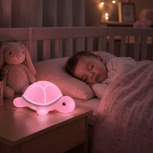 Veilleuse tortue rose diffusant une lumière douce sur une table de chevet dans la chambre d'un bébé endormi